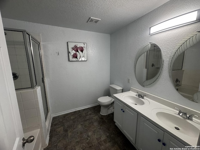 bathroom featuring vanity, a shower with door, toilet, and a textured ceiling