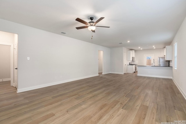 unfurnished living room featuring ceiling fan, sink, and light hardwood / wood-style floors