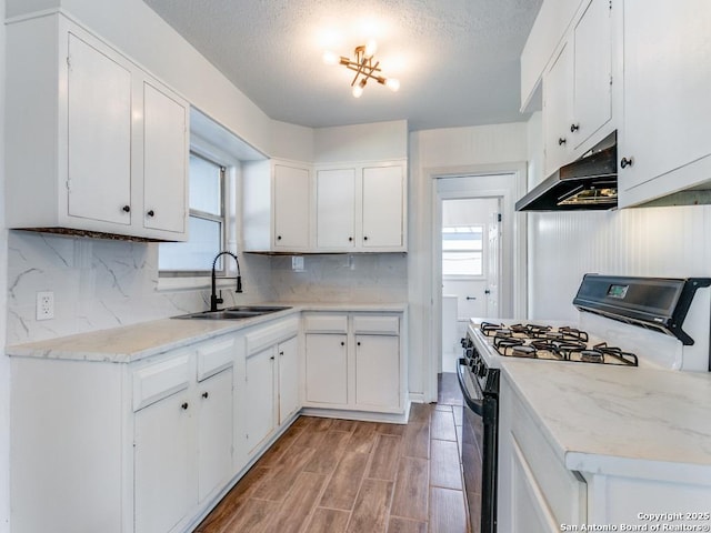 kitchen with black gas stove, sink, white cabinets, and light hardwood / wood-style floors