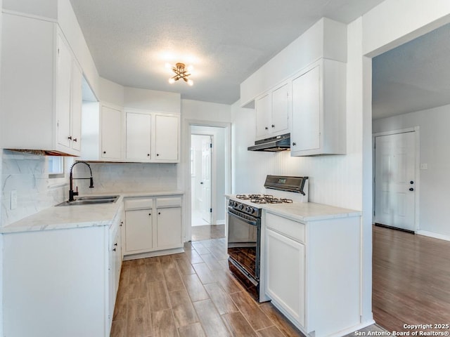 kitchen with sink, backsplash, range with gas cooktop, and white cabinets