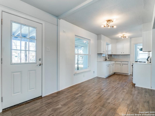 kitchen featuring sink, an inviting chandelier, hardwood / wood-style floors, tasteful backsplash, and white cabinets