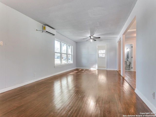 empty room featuring ceiling fan, dark hardwood / wood-style floors, and a wall mounted AC