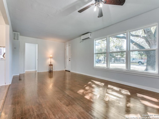 unfurnished living room featuring dark wood-type flooring, ceiling fan, a wall mounted air conditioner, and plenty of natural light