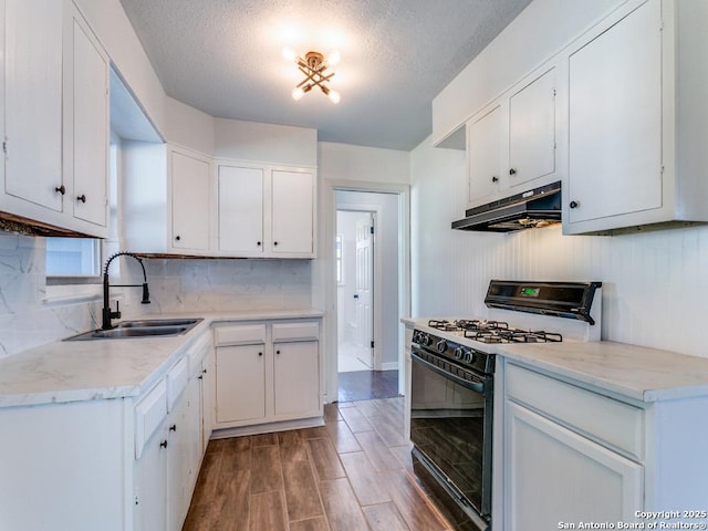 kitchen with white cabinetry, sink, backsplash, gas range oven, and a textured ceiling