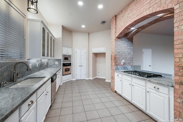 kitchen with appliances with stainless steel finishes, sink, backsplash, white cabinets, and light stone counters