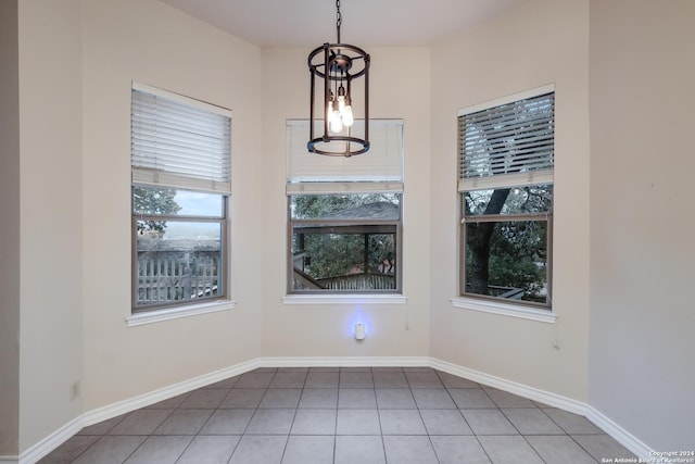 unfurnished dining area featuring an inviting chandelier and tile patterned flooring