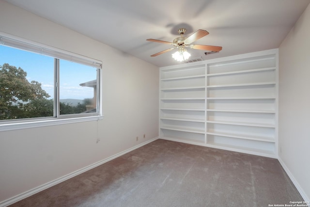 spare room featuring carpet floors, built in features, and ceiling fan