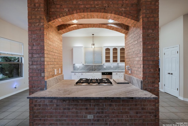 kitchen featuring dark tile patterned floors, appliances with stainless steel finishes, hanging light fixtures, tasteful backsplash, and white cabinets