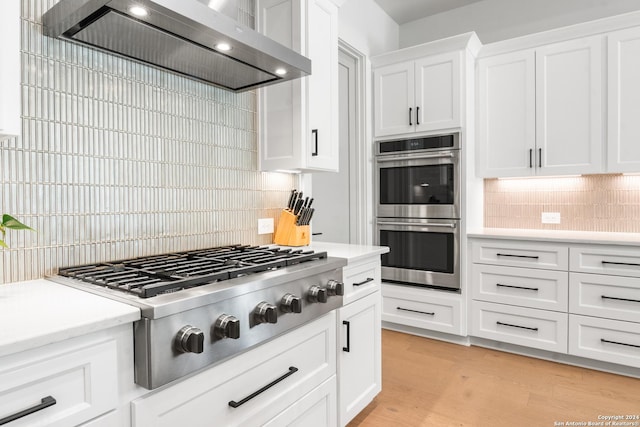 kitchen with white cabinetry, backsplash, wall chimney exhaust hood, and appliances with stainless steel finishes