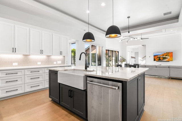 kitchen featuring white cabinetry, light hardwood / wood-style flooring, dishwasher, pendant lighting, and a kitchen island with sink