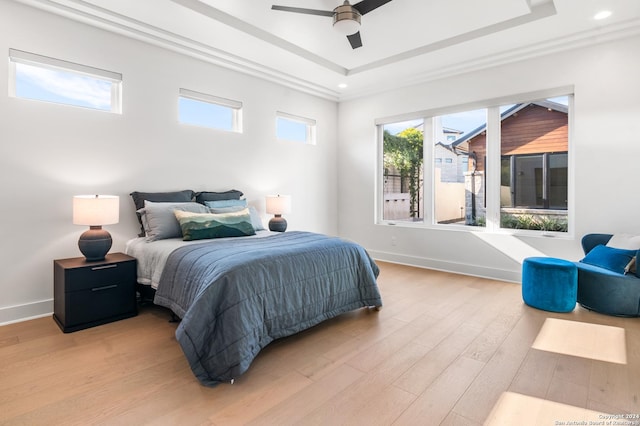 bedroom featuring ceiling fan, a tray ceiling, and light hardwood / wood-style floors