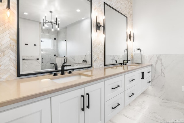 bathroom with vanity, a shower with door, tile walls, and an inviting chandelier