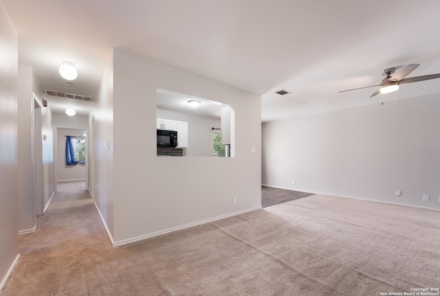 empty room featuring plenty of natural light, light carpet, and ceiling fan