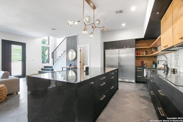 kitchen with stainless steel built in refrigerator, sink, hanging light fixtures, a kitchen island, and backsplash