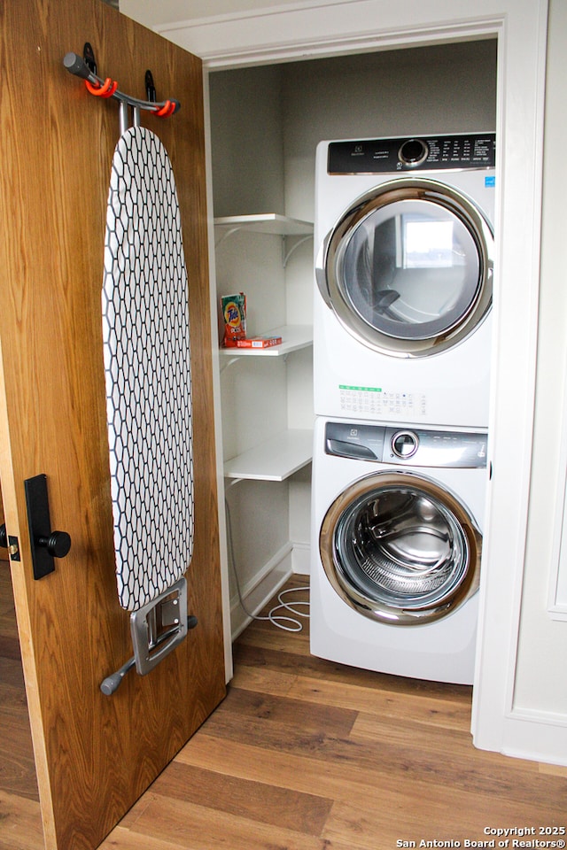 laundry room featuring dark wood-type flooring and stacked washer and dryer