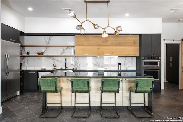 kitchen with a breakfast bar, appliances with stainless steel finishes, hanging light fixtures, tasteful backsplash, and a kitchen island