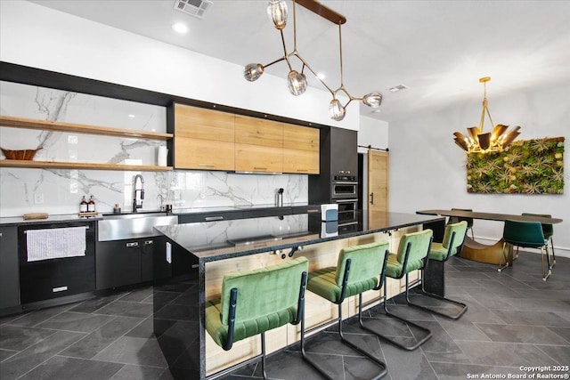 kitchen featuring sink, tasteful backsplash, decorative light fixtures, dishwasher, and a barn door