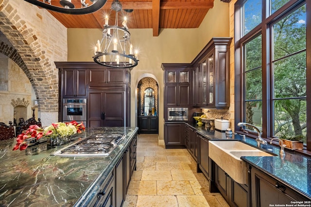 kitchen with pendant lighting, a chandelier, built in appliances, wood ceiling, and dark brown cabinetry