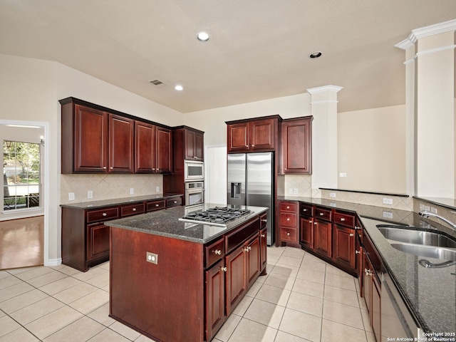 kitchen with light tile patterned flooring, sink, ornate columns, dark stone counters, and stainless steel appliances