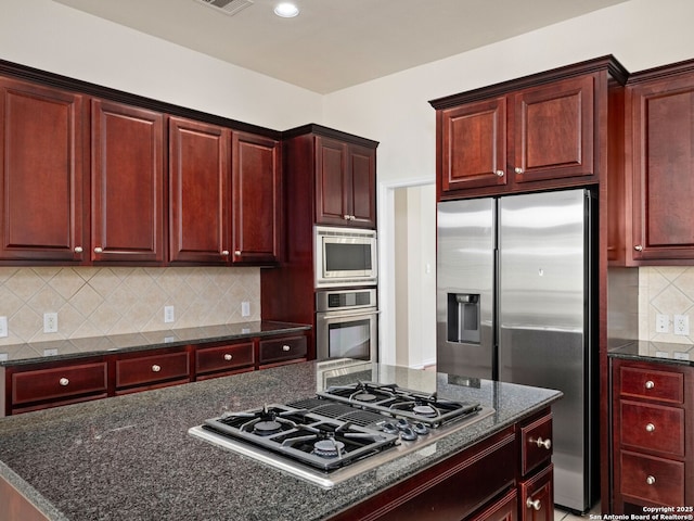 kitchen with backsplash, stainless steel appliances, and dark stone countertops