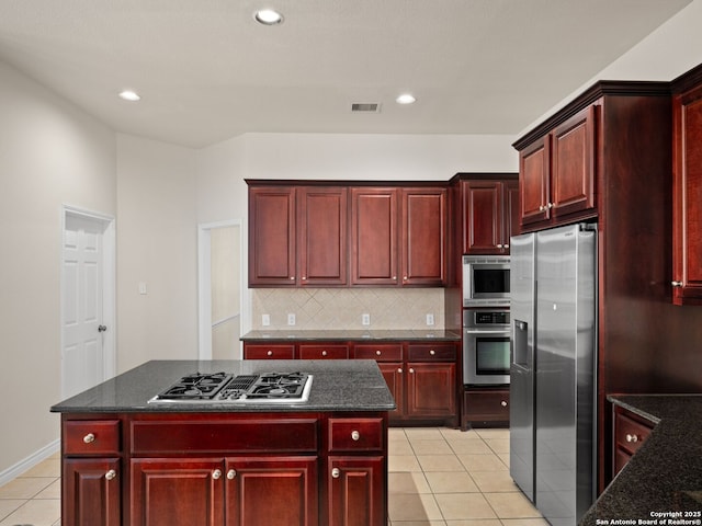 kitchen featuring light tile patterned flooring, appliances with stainless steel finishes, a center island, and decorative backsplash