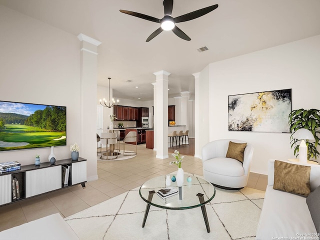 tiled living room featuring ceiling fan with notable chandelier and decorative columns