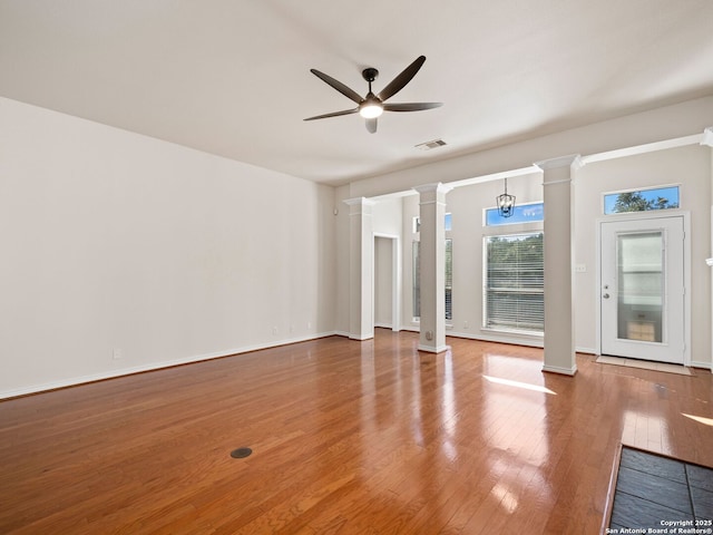 interior space with decorative columns, wood-type flooring, and ceiling fan