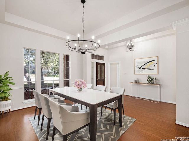 dining area with an inviting chandelier, a tray ceiling, and dark hardwood / wood-style floors