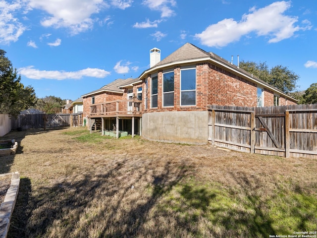 rear view of property featuring a wooden deck and a yard