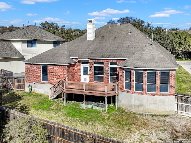 back of property with a wooden deck and a lawn