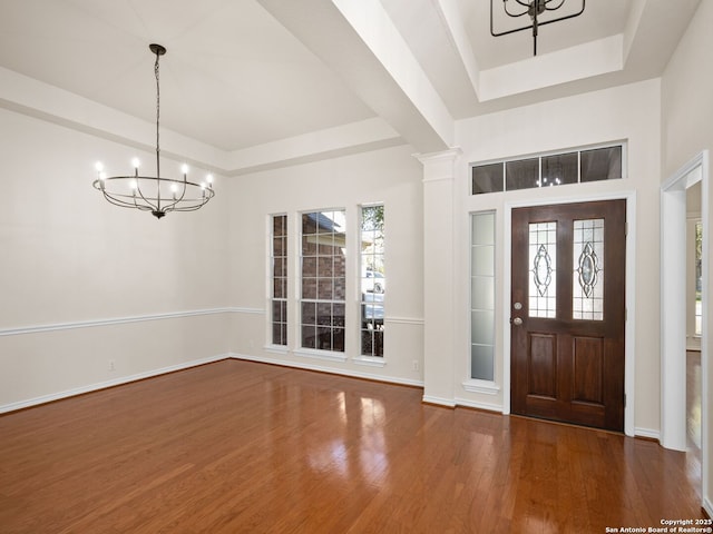 foyer featuring hardwood / wood-style floors, a chandelier, and a tray ceiling