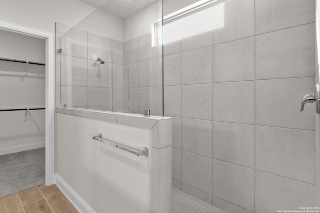 bathroom with tiled shower and hardwood / wood-style floors