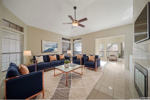 tiled living room with ceiling fan, lofted ceiling, and a fireplace