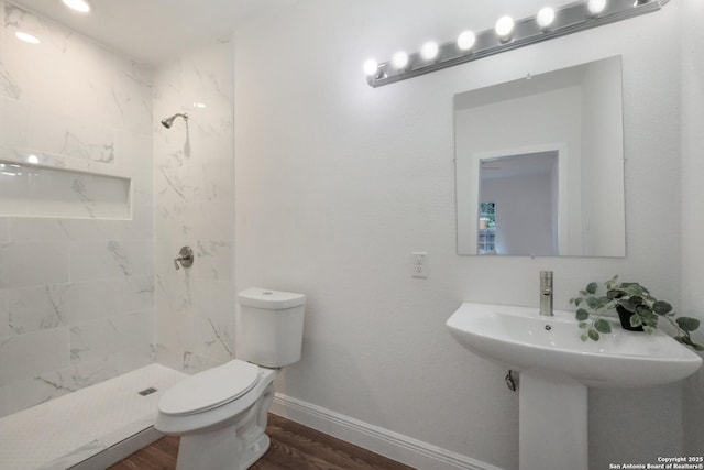 bathroom with wood-type flooring, toilet, and tiled shower