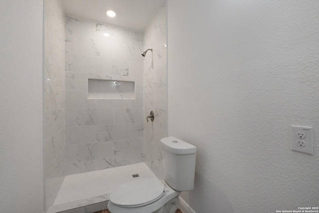 bathroom featuring tiled shower and toilet