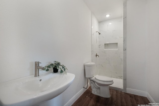 bathroom featuring sink, hardwood / wood-style flooring, toilet, and tiled shower