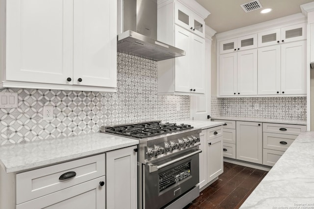 kitchen featuring white cabinets, high end range, light stone counters, dark wood-type flooring, and wall chimney range hood