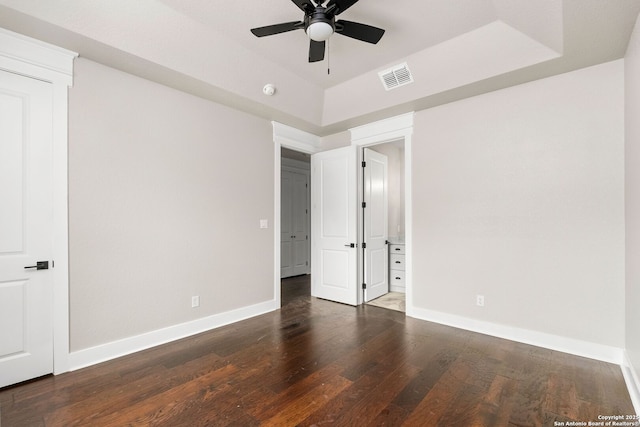 unfurnished bedroom with a raised ceiling, ceiling fan, and dark hardwood / wood-style flooring