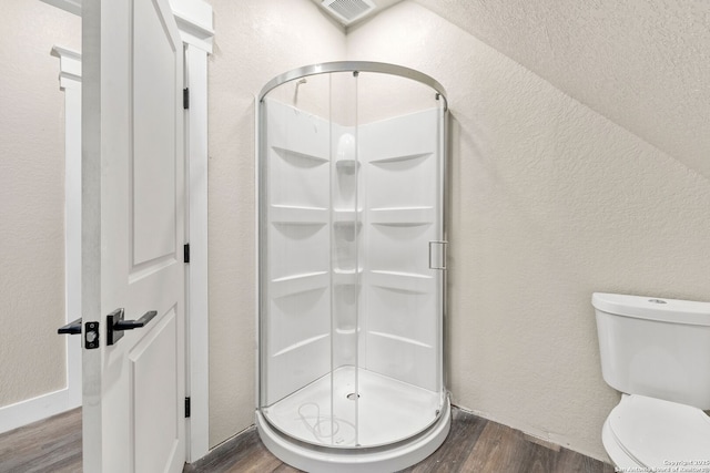 bathroom featuring wood-type flooring, an enclosed shower, and toilet