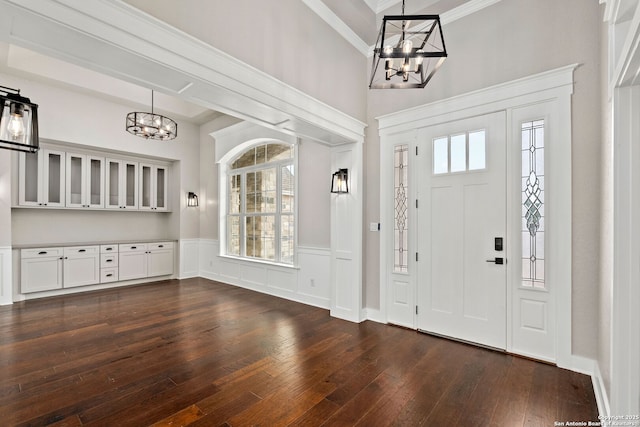 foyer with dark hardwood / wood-style flooring, ornamental molding, and an inviting chandelier