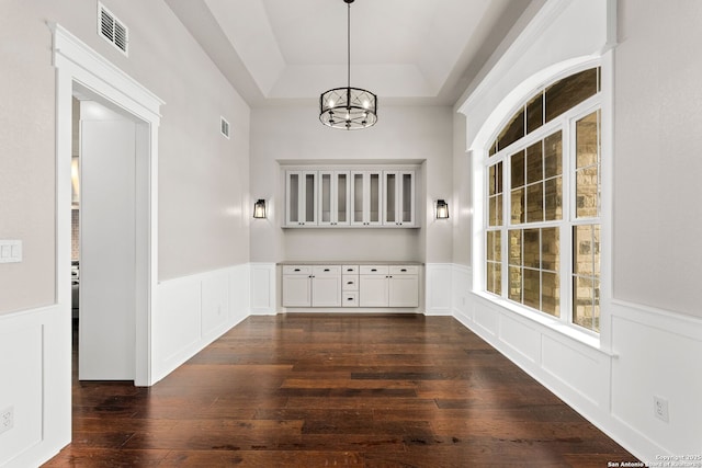 interior space featuring dark wood-type flooring, a tray ceiling, and an inviting chandelier