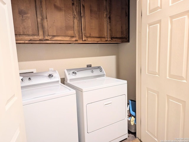 clothes washing area with cabinets and washing machine and dryer