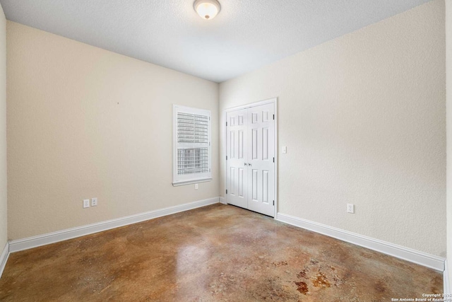 unfurnished room with concrete flooring and a textured ceiling