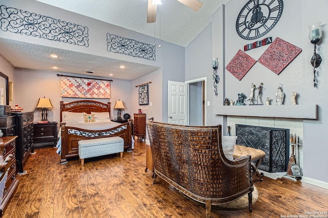 bedroom with wood-type flooring, a tiled fireplace, and a textured ceiling