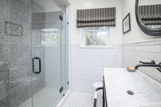 bathroom featuring tile walls, vanity, a shower with shower door, and toilet