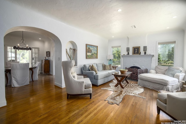 living room featuring dark wood-type flooring, a wealth of natural light, a fireplace, and a chandelier