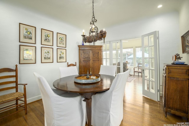 dining space featuring hardwood / wood-style flooring, french doors, and a notable chandelier