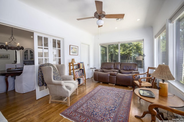 living room featuring hardwood / wood-style flooring and ceiling fan with notable chandelier