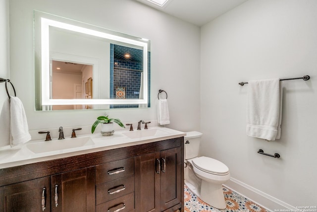 full bathroom featuring double vanity, baseboards, toilet, and a sink