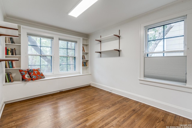 empty room with ornamental molding, plenty of natural light, and wood finished floors